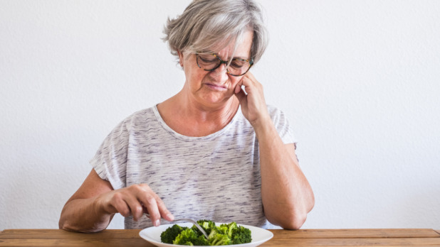 vrouw kijkt vies naar haar bord met eten