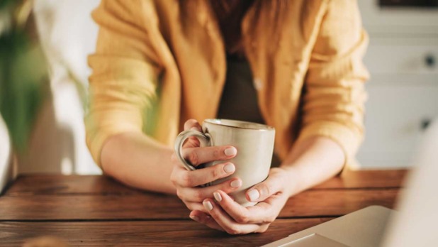 Vrouw drinkt koffie achter laptop