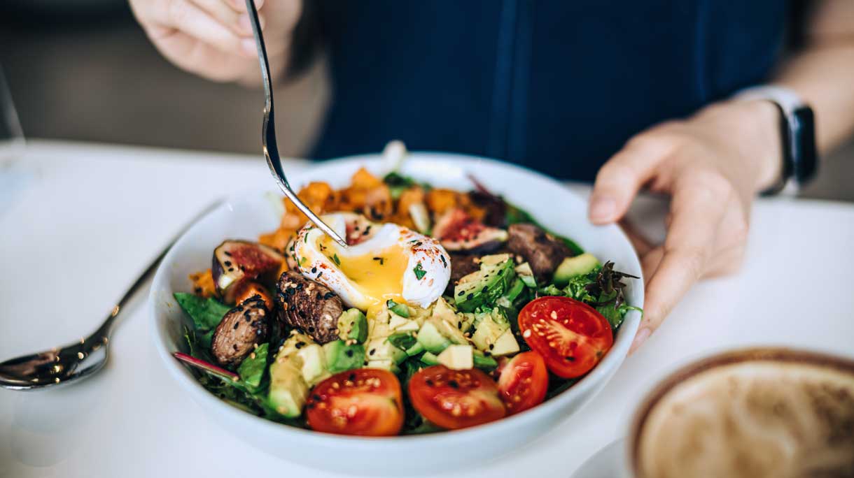 Vrouw eet salade met ei