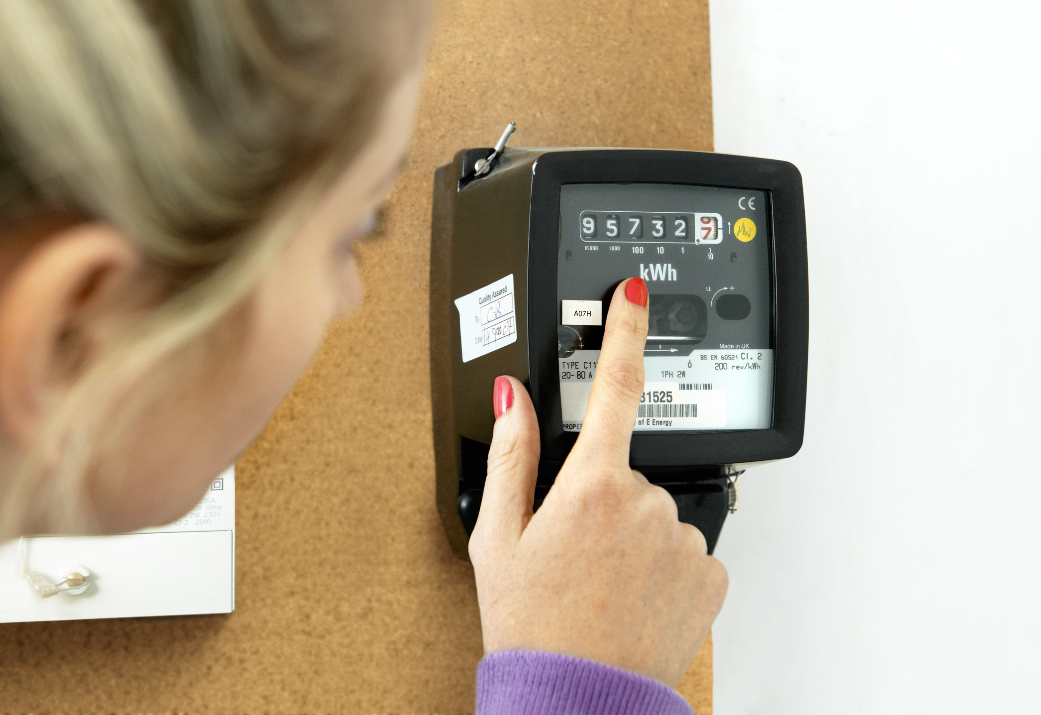 Vrouw wijst naar stroom meter