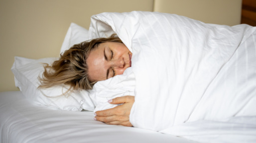 Vrouw ligt in bed op haar zij in wit dekbed