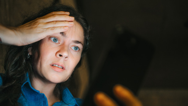 Vrouw kijkt verschikt op haar telefoon