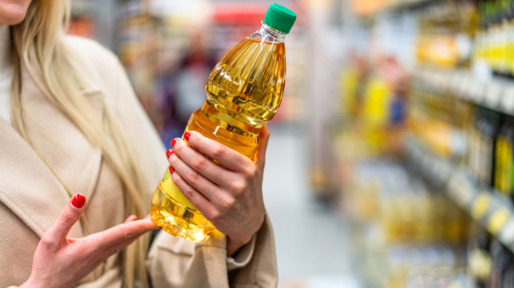 Vrouw in de supermarkt met een fles zonnebloemolie in haar hand