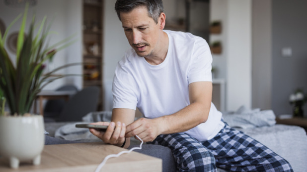 Man legt telefoon aan oplader