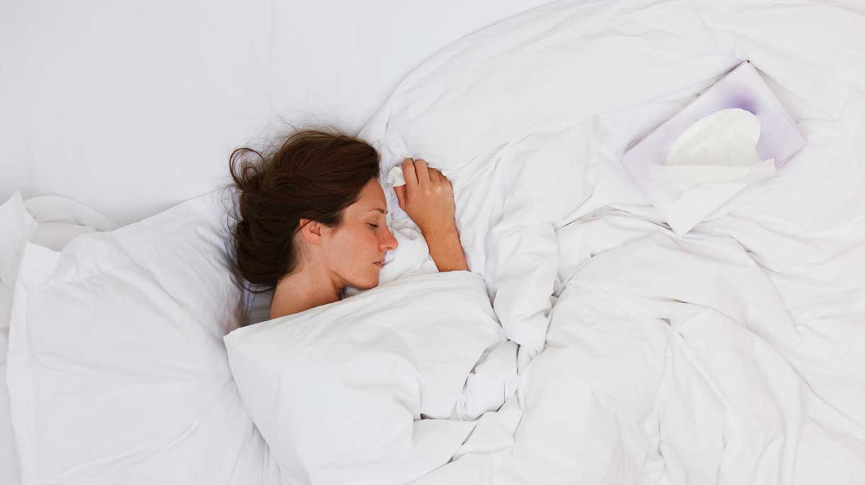 vrouw ligt met verkoudheid in bed