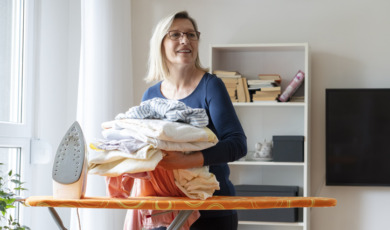 Oudere dame doet strijkwerk thuis