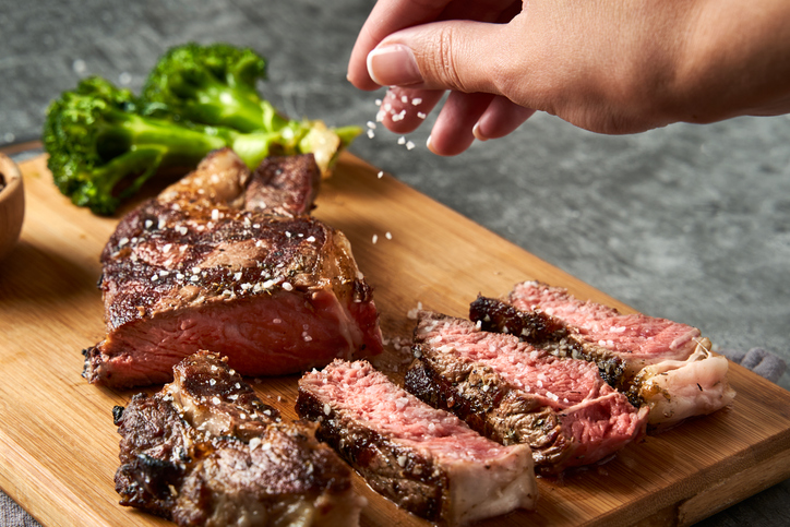 Man bestrooit steak met zout