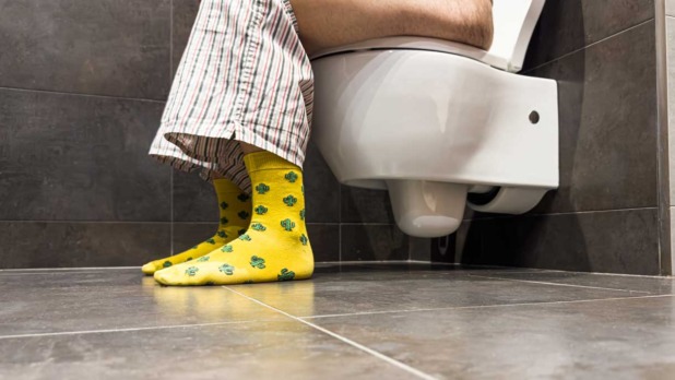Man zittend op toilet