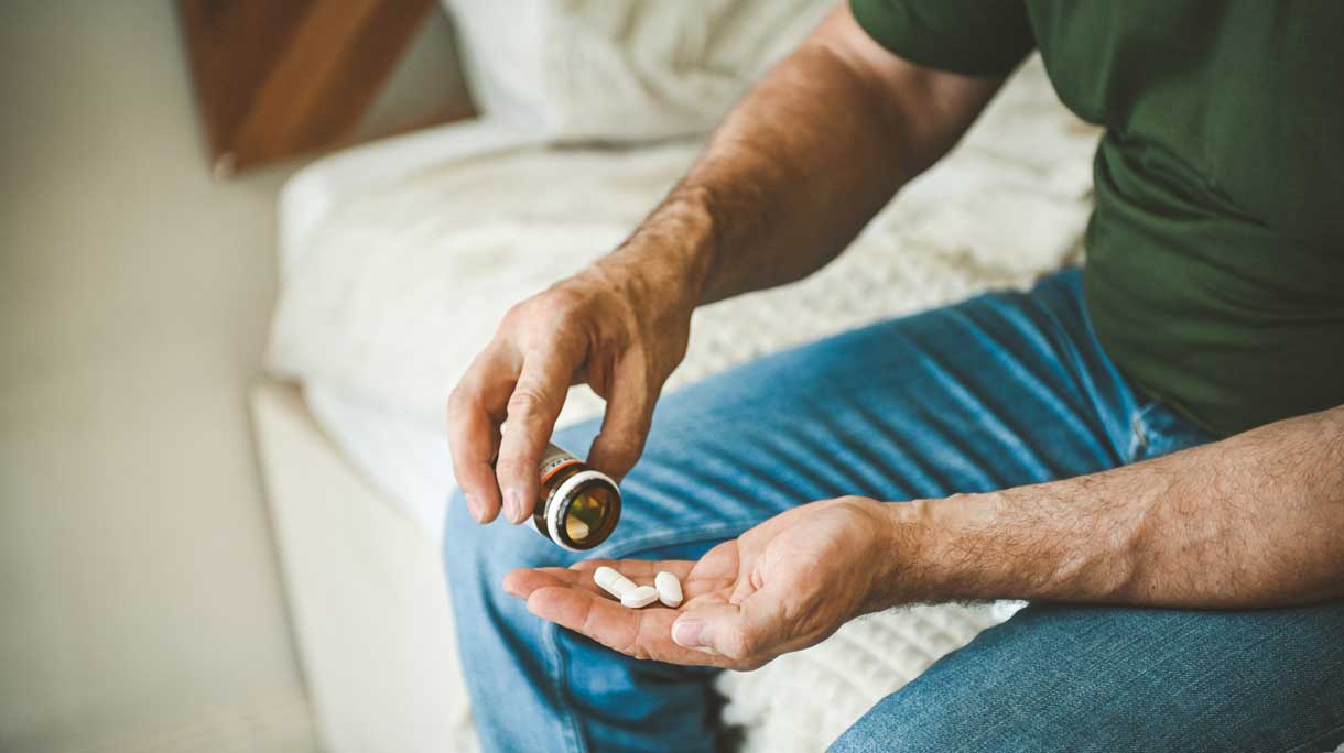 Man zit op rand van het bed neemt erectiepil