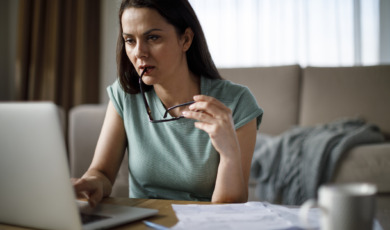 Vrouw in groene sweater is thuis bezig met belastingzaken achter laptop