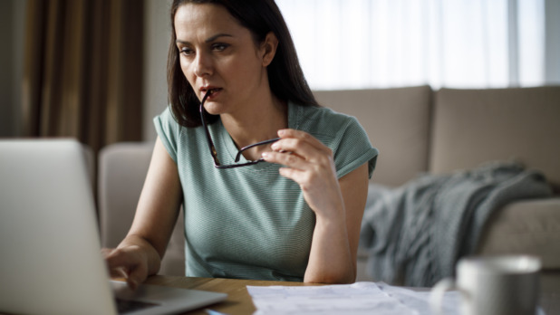 Vrouw in groene sweater is thuis bezig met belastingzaken achter laptop