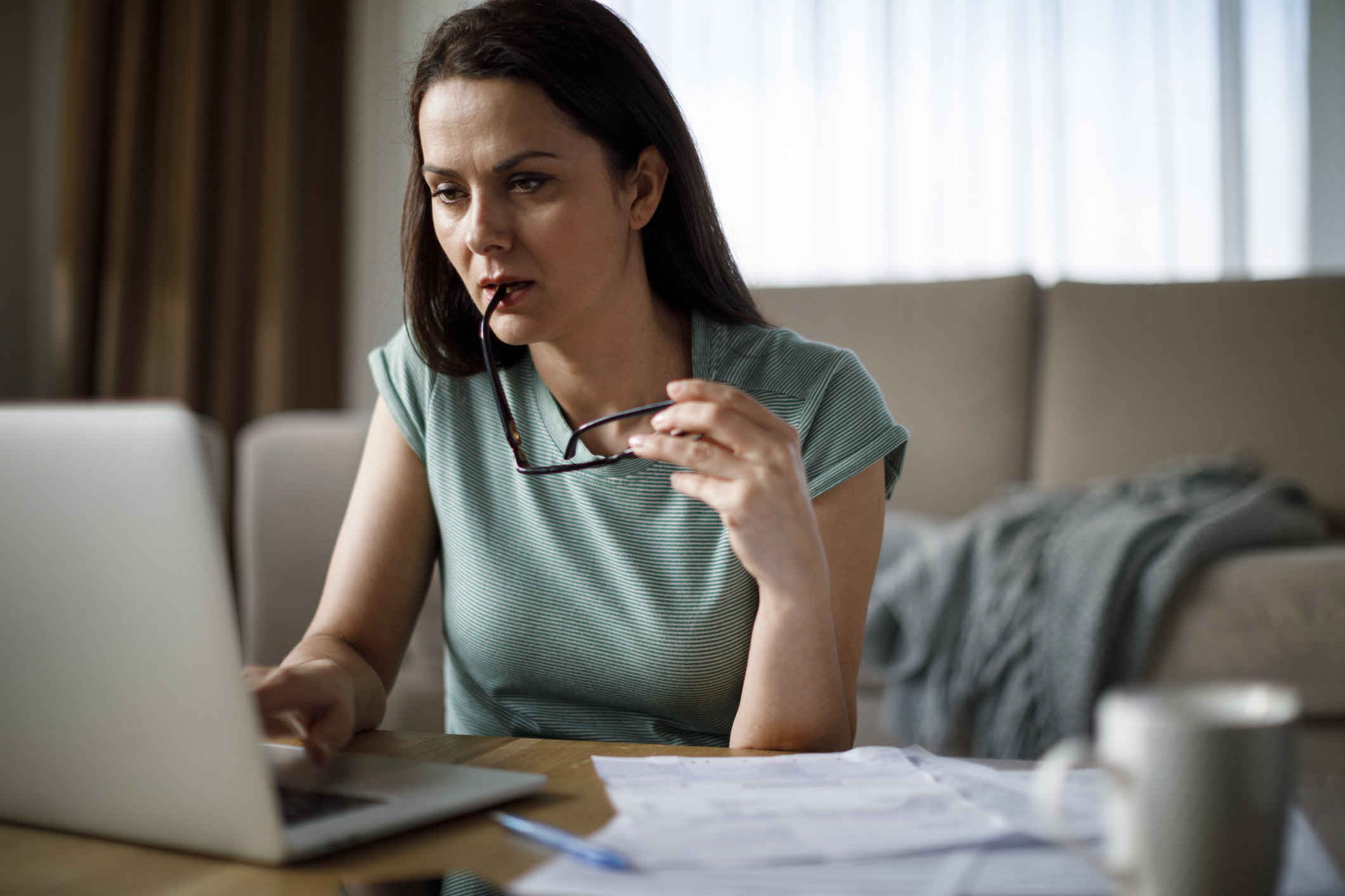 Vrouw in groene sweater is thuis bezig met belastingzaken achter laptop