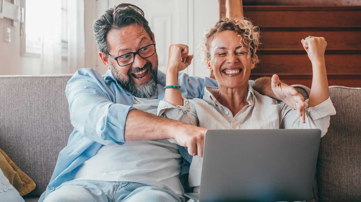 Vrouw en man zien dat ze de loterij gewonnen hebben op laptop