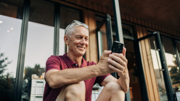 Man speelt met smartphone op veranda vakantiehuis