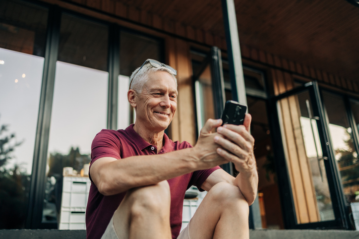Man speelt met smartphone op veranda vakantiehuis
