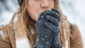 Vrouw heeft koude handen in haar handschoenen want het sneeuwt