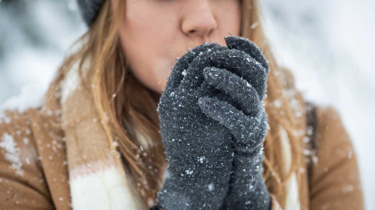 Vrouw heeft koude handen in haar handschoenen want het sneeuwt