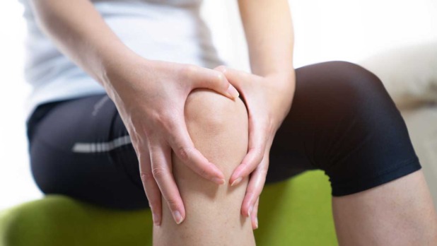 Vrouw met haar handen om haar pijnlijke knie