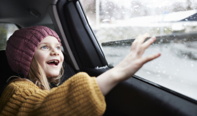 Meisje zit in besneeuwde auto