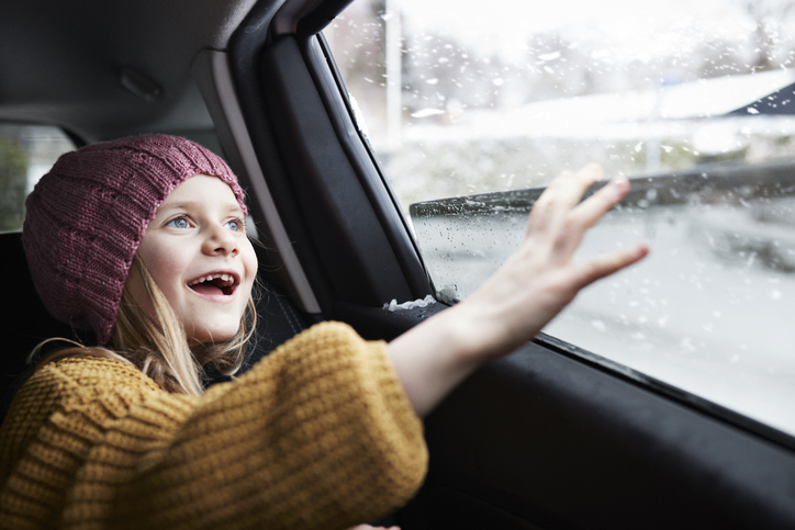 Meisje zit in besneeuwde auto