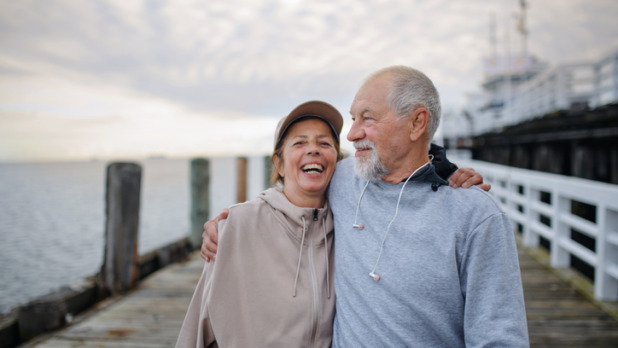 Man en vrouw lopen lachend over pier
