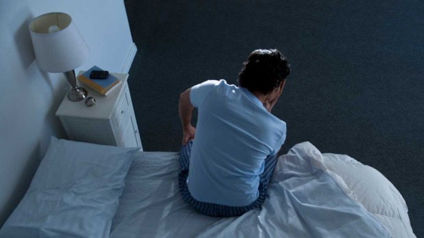 Man op de rand van een bed