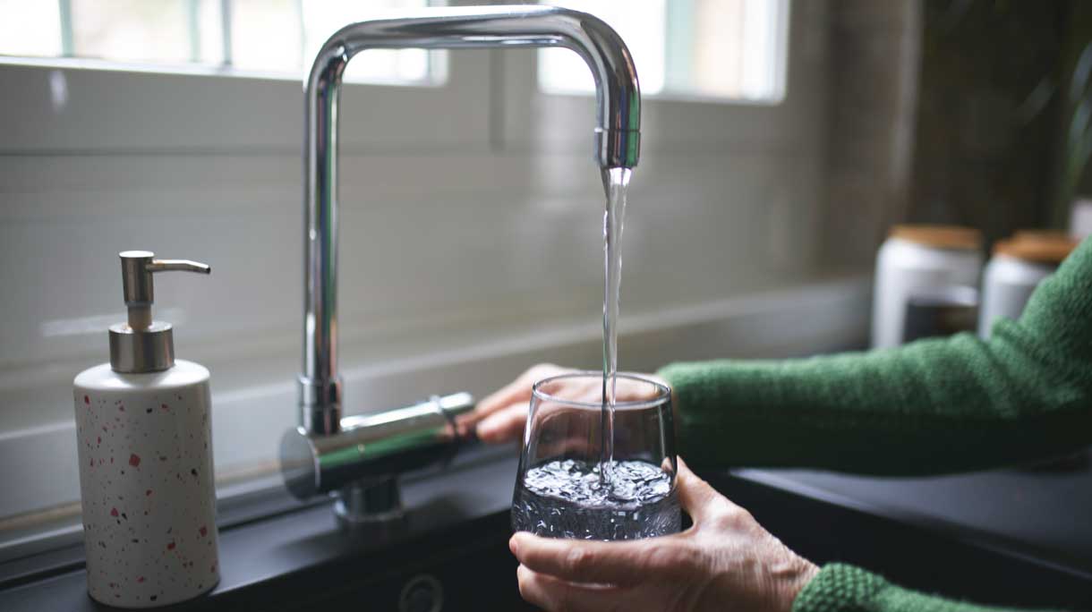 vrouw vult glas water aan kraan