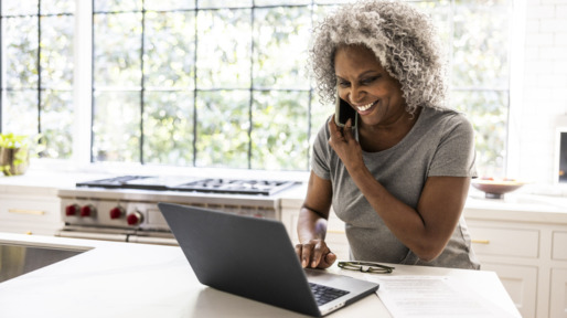 Vrouw met grijze afro zit achter laptop