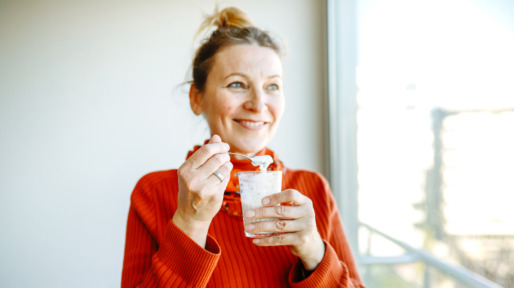 lachende vrouw eet yoghurt