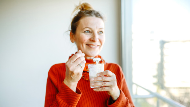 lachende vrouw eet yoghurt