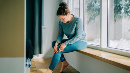 Vrouw voelt aan haar knie die zeer doet