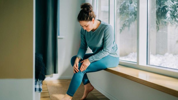 Vrouw voelt aan haar knie die zeer doet