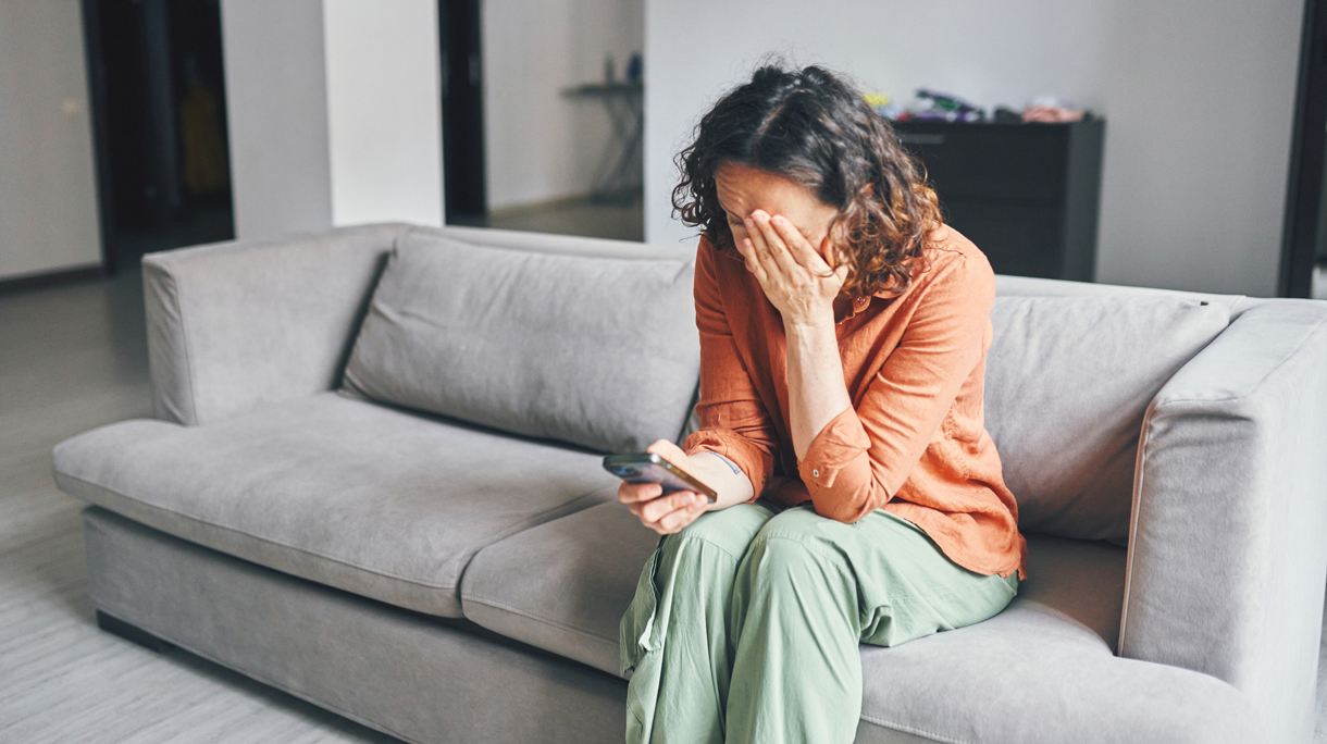 vrouw kijkt somber naar haar telefoon