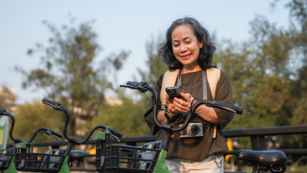 Oudere dame checkt haar smartphone bij fietsenstalling