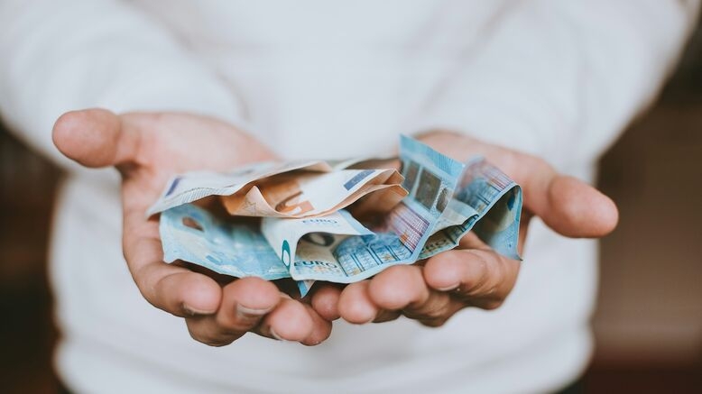 Twee handen die geldbiljetten en euromunten vasthouden
