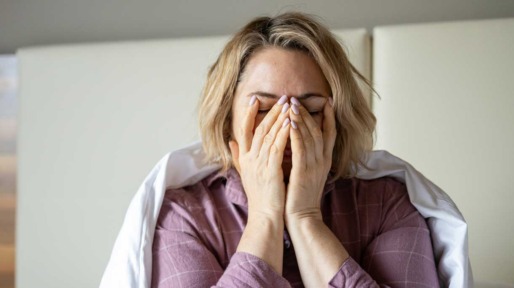 Vrouw zit vermoeid op bed na een slechte nacht slapen