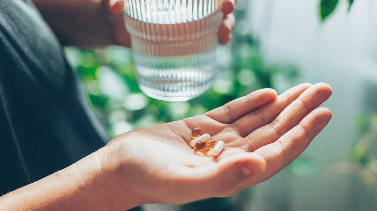 vrouw met glas water en vitamines