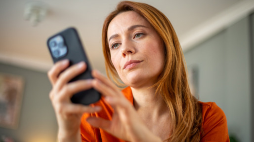 Vrouw met lang rood haar checkt smartphone