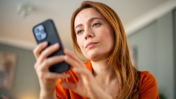 Vrouw met lang rood haar checkt smartphone