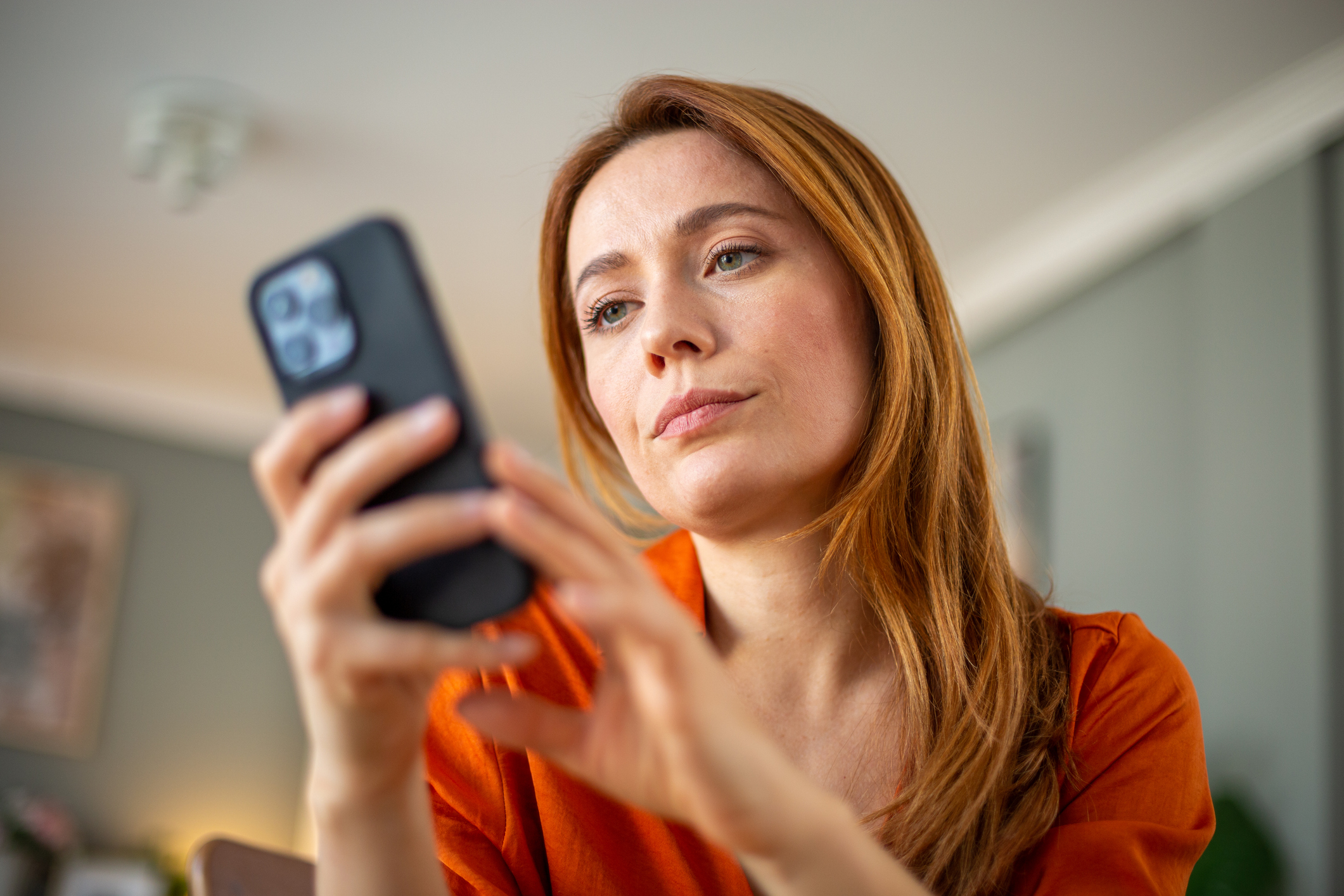 Vrouw met lang rood haar checkt smartphone