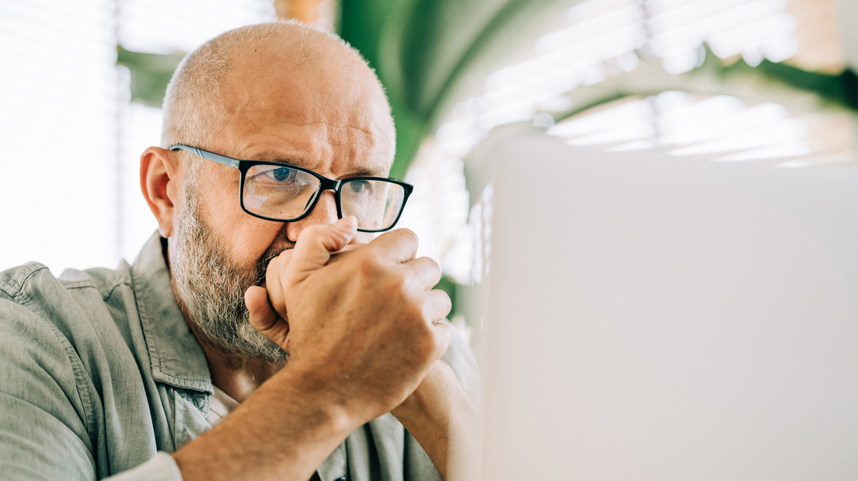 oudere man kijkt bezorgd naar laptop