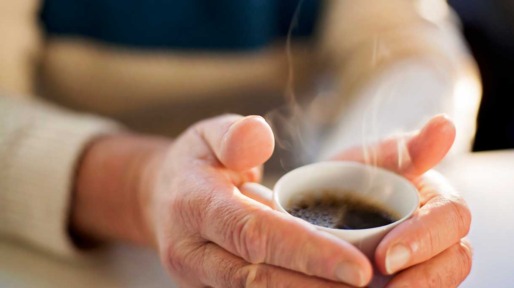 Vrouw warmt haar handen aan een kop koffie