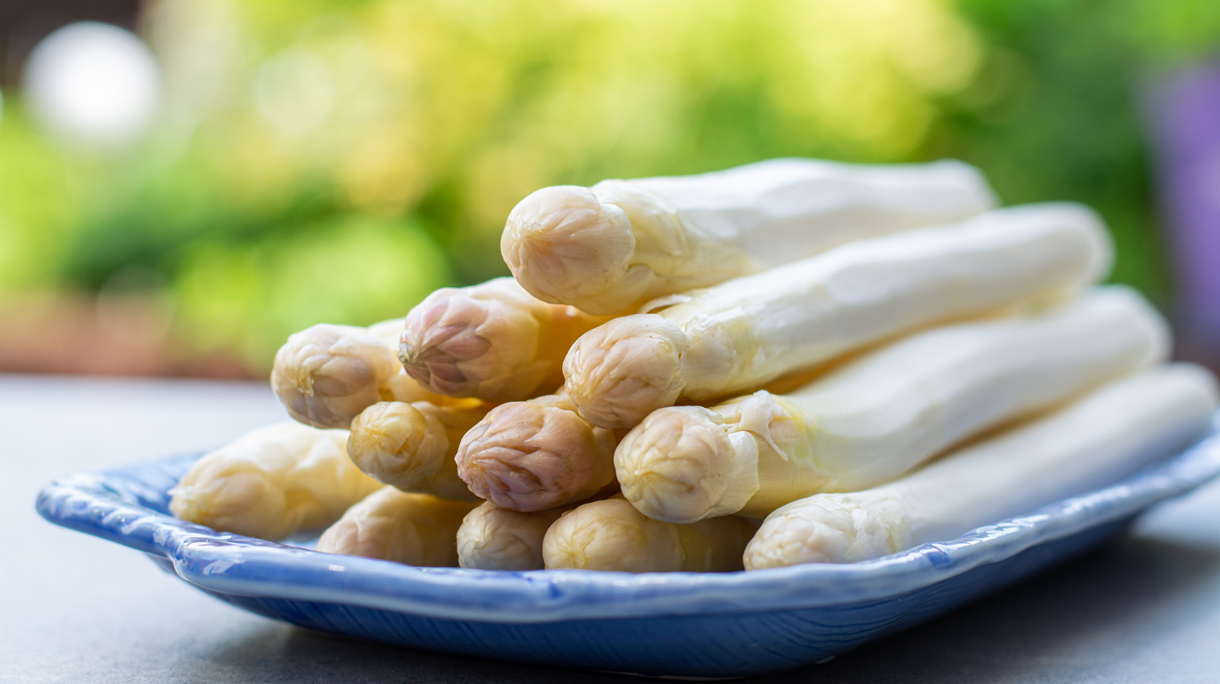 Witte asperges liggend op een blauw bord