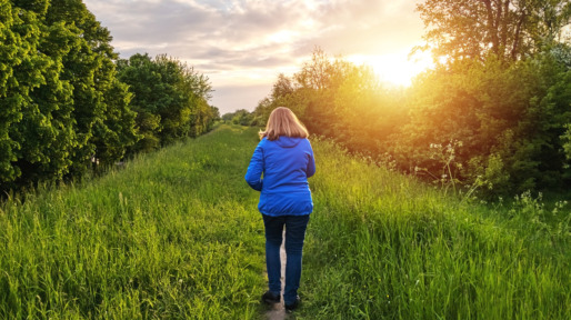 Vrouw loopt over dijk in het opkomende zonnetje