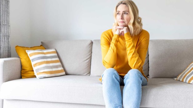Vrouw zit op de bank en denkt na