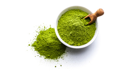 Matcha in een potje met een houten lepel op een witte achtergrond