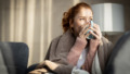 Vrouw net wakker zit op bed en drinkt een kop koffie