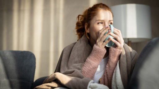 Vrouw net wakker zit op bed en drinkt een kop koffie