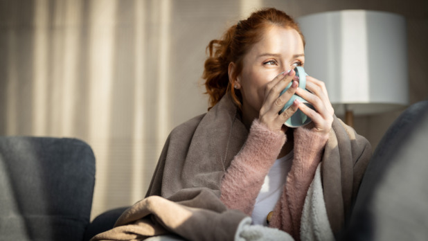 Vrouw net wakker zit op bed en drinkt een kop koffie