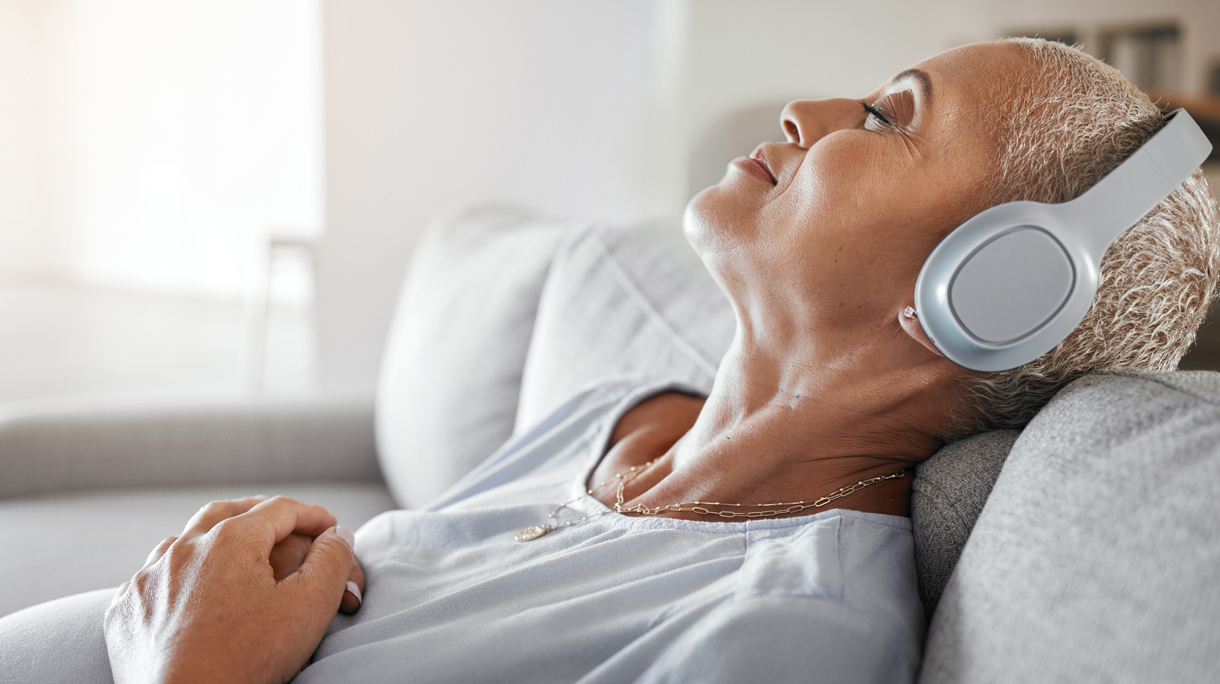 Vrouw ligt op de bank en luistert naar een podcast